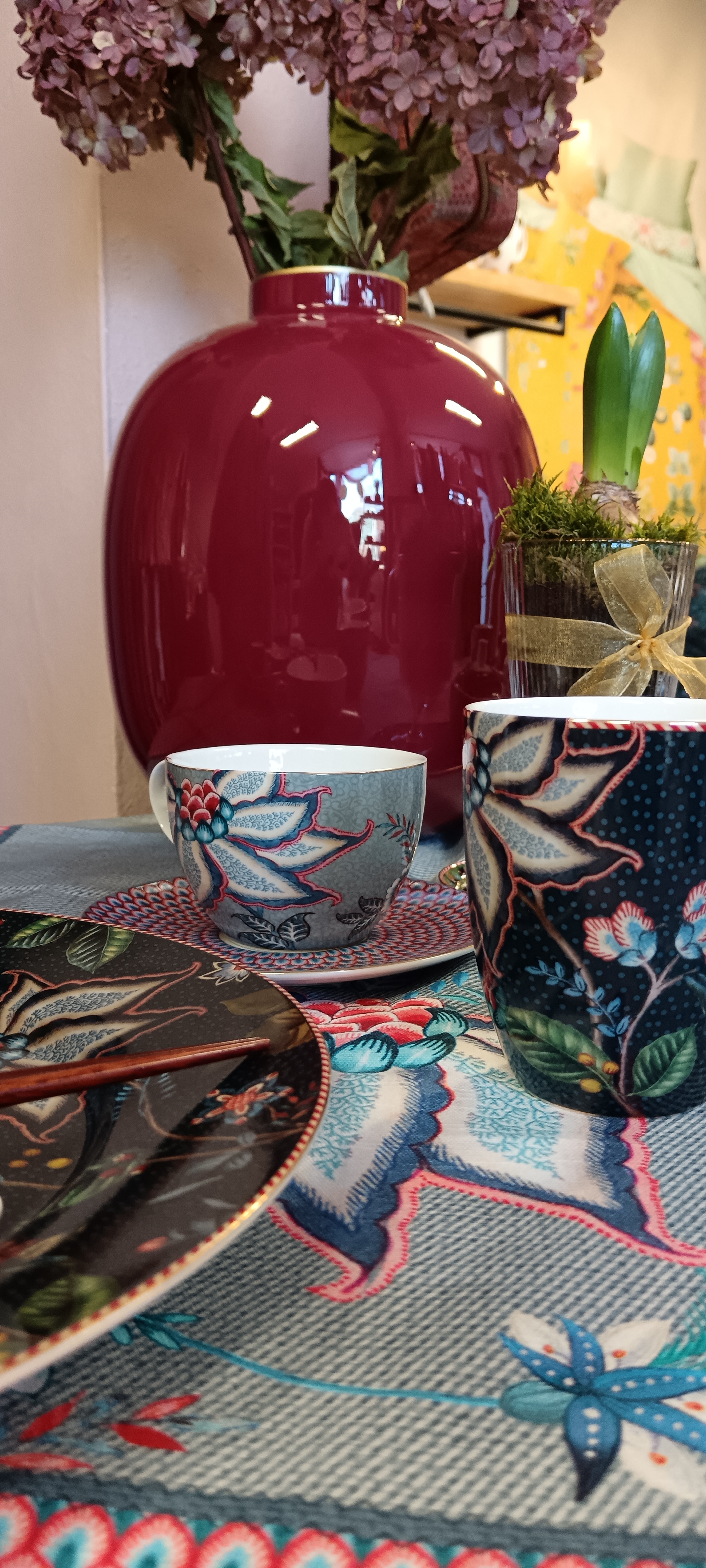 tmavě červená velká váza Pip Studio, hrnek Flower Festival modrý na cappuccino, talíř velký třicet dva centimetru Berry Blues a hrnek tmavě modrý na modrém ubrusu s velkými květy